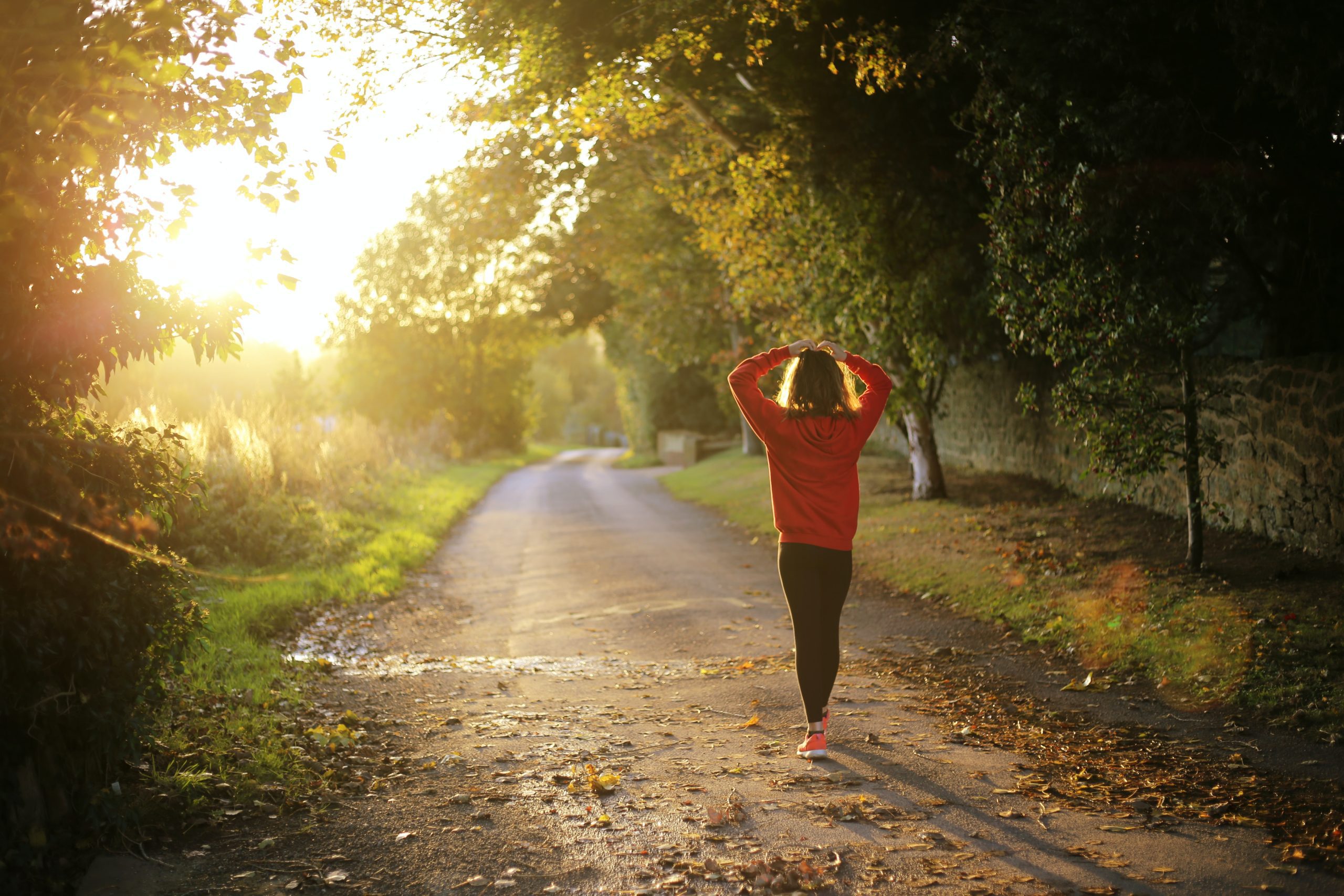Woman cooling down and stretching arms after an early morning run