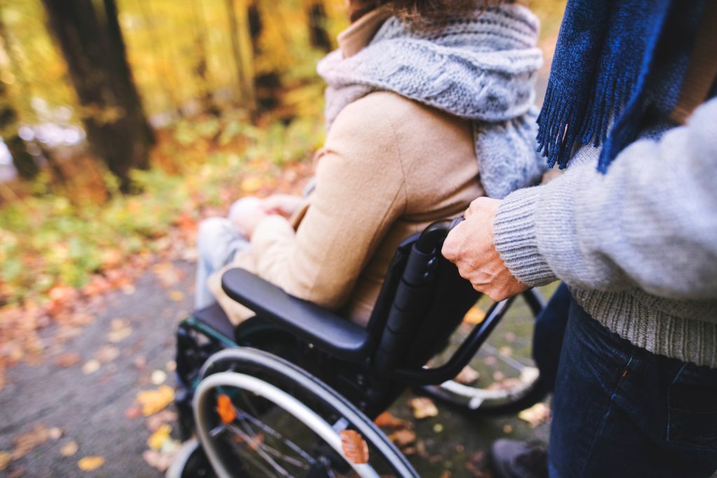 An aide pushing a person in a wheelchair