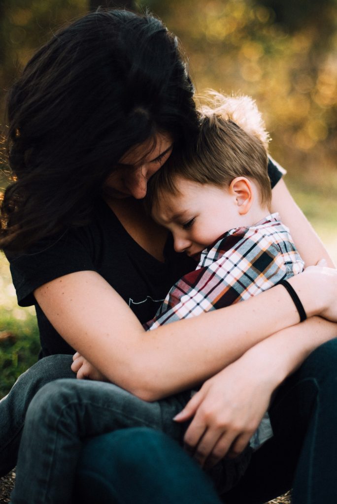 A mother holding and consoling her young son