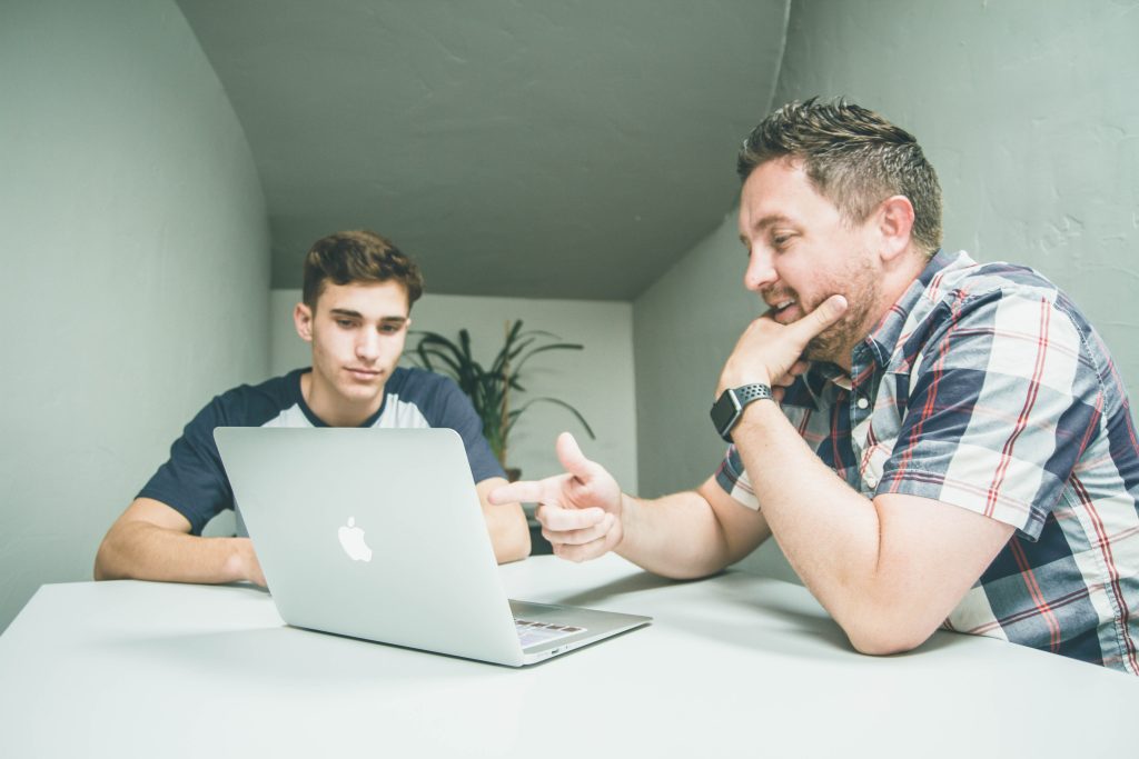 Father and teenage son working on a laptop