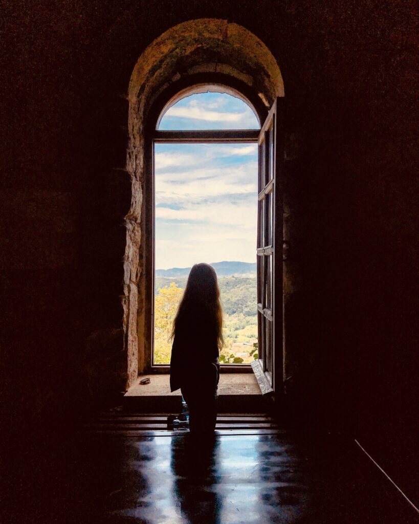 Girl with long hair looking through an open window