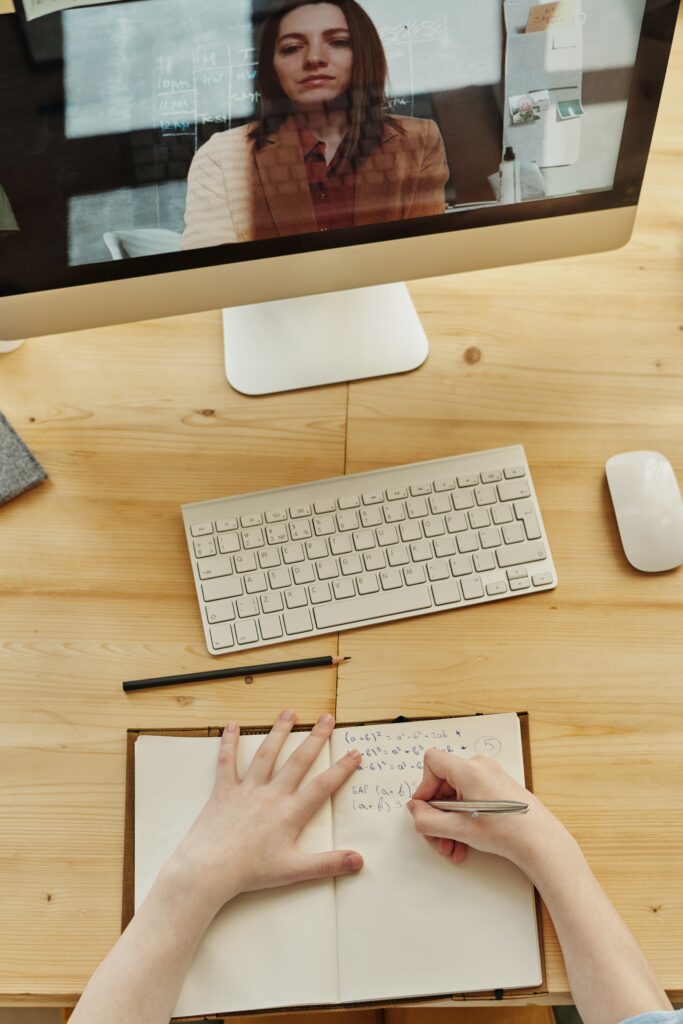 person writing notes in virtual meeting