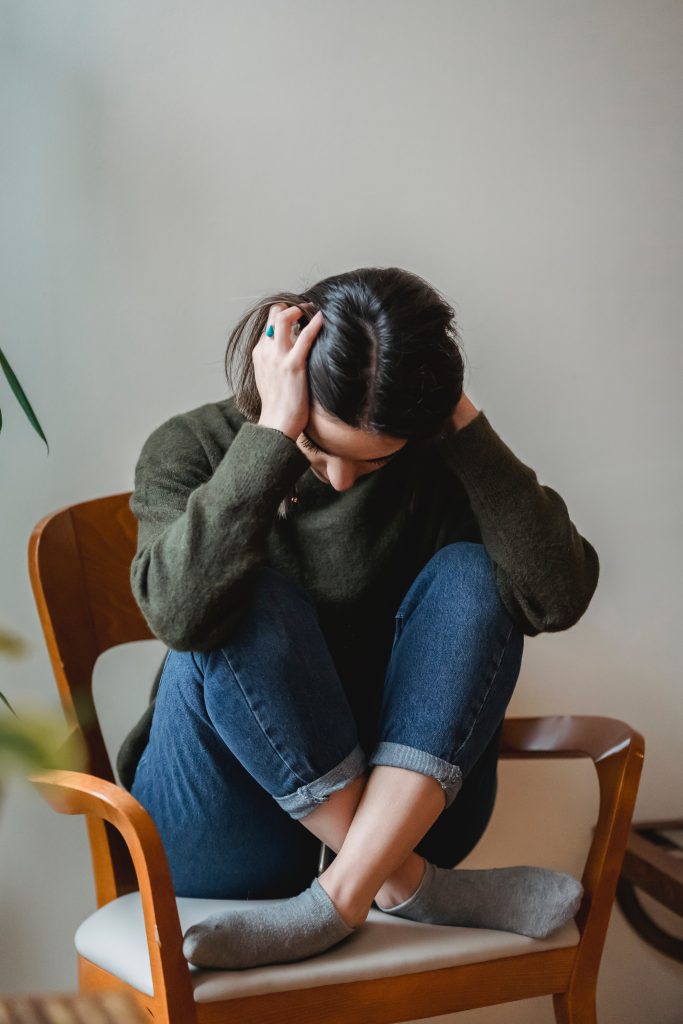 Woman crunched in a chair covering her ears