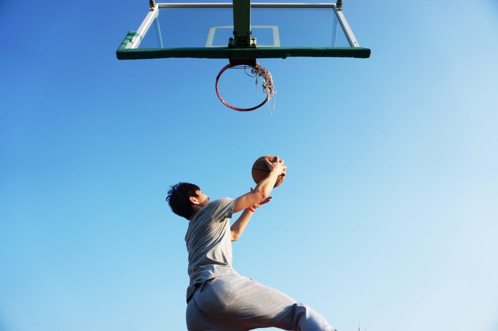 Young man underneath a basketball hoop about to do a reverse lay up