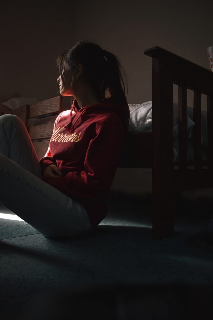 Teenage girl in a dark room looking outside