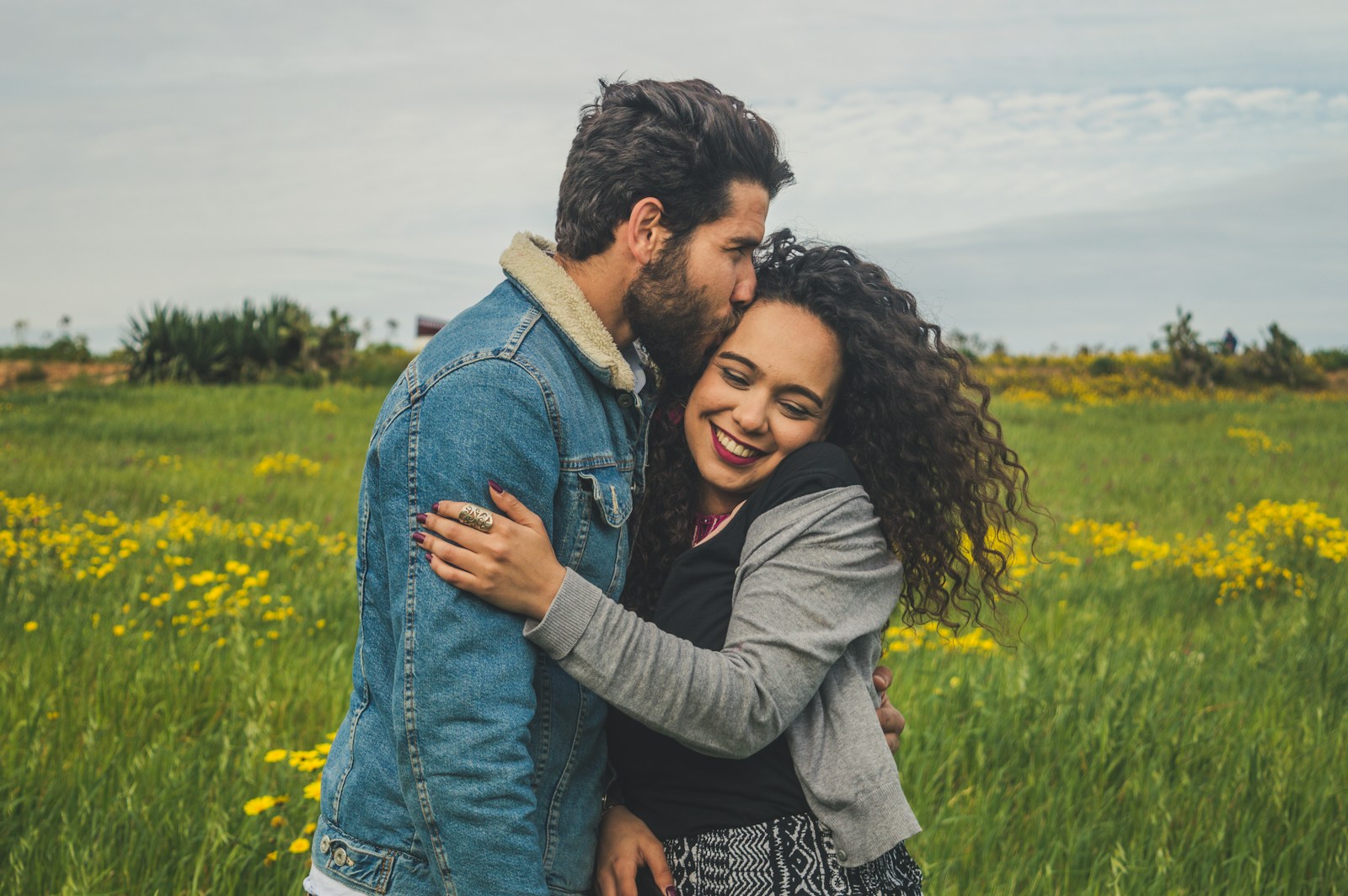 couples counselling man kissing on woman's head on the green grassy field